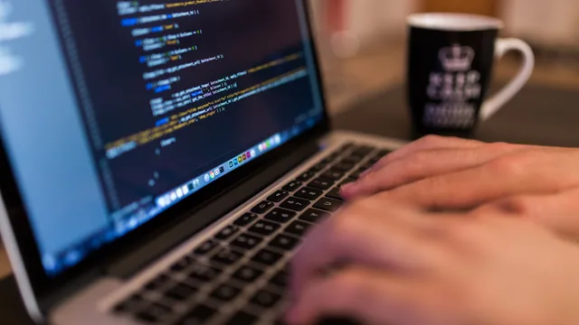 Software developer at workstation reviewing open-source code repositories across multiple displays